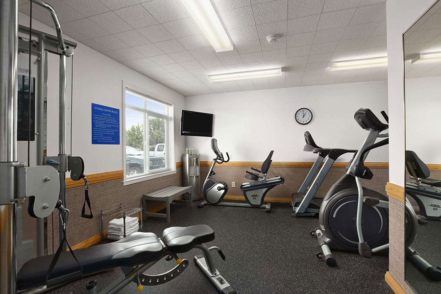 fitness center with weight machines, cardio machines, towels, and water cooler at Days Inn by Wyndham Great Falls